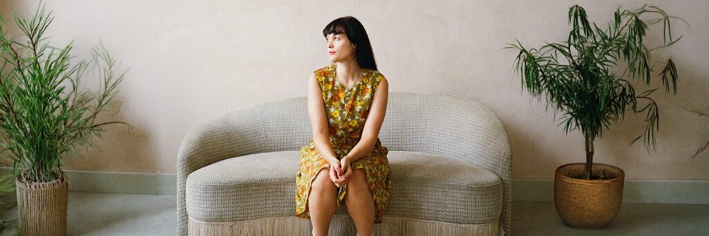 One soloist shown, indoors, with two potted plants and a couch